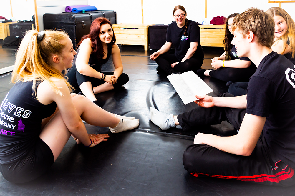 The Nine Lives Theatre Company cast sit to review their rehearsal and the text.